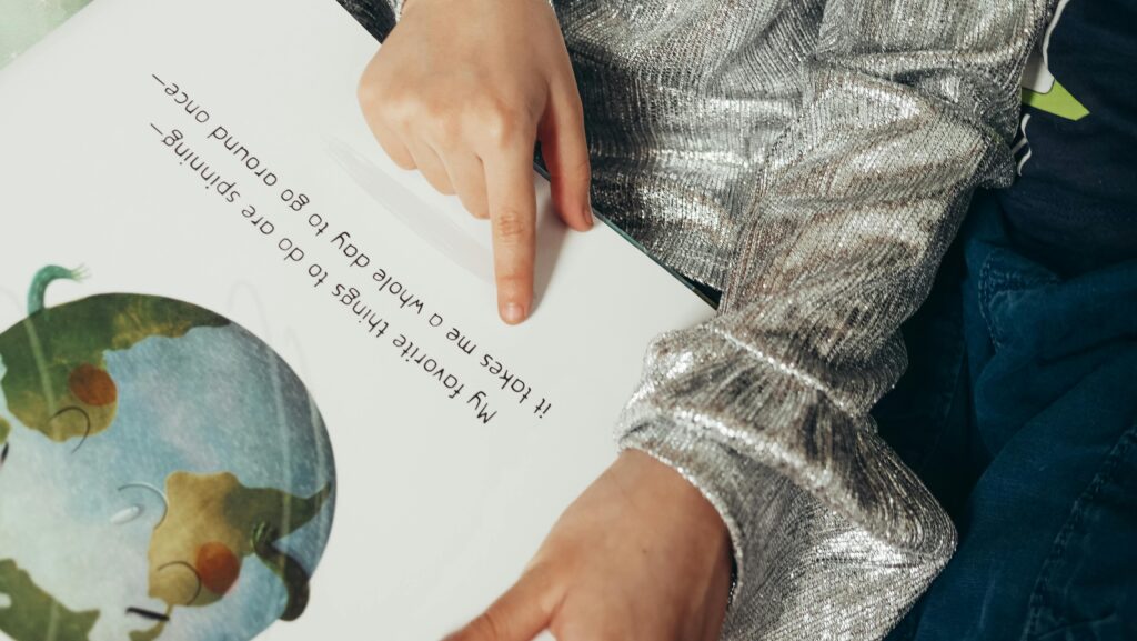 pexels-photo-7105618-7105618 A child pointing to text in an illustrated book, showcasing reading and learning.